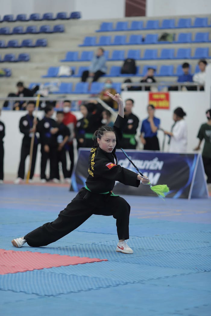 Martial artist showcasing skills during an indoor tournament, captured in action.